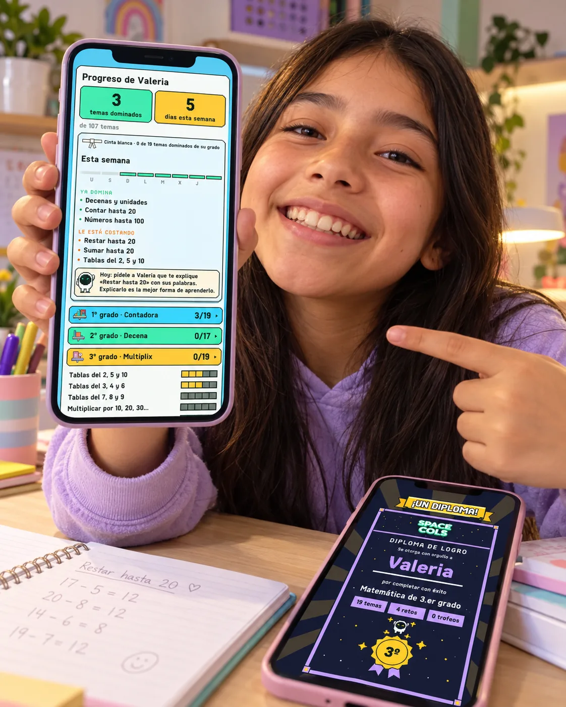 Niña muestra su progreso en Spacecols y, en otro teléfono, su diploma de matemática de 3.er grado